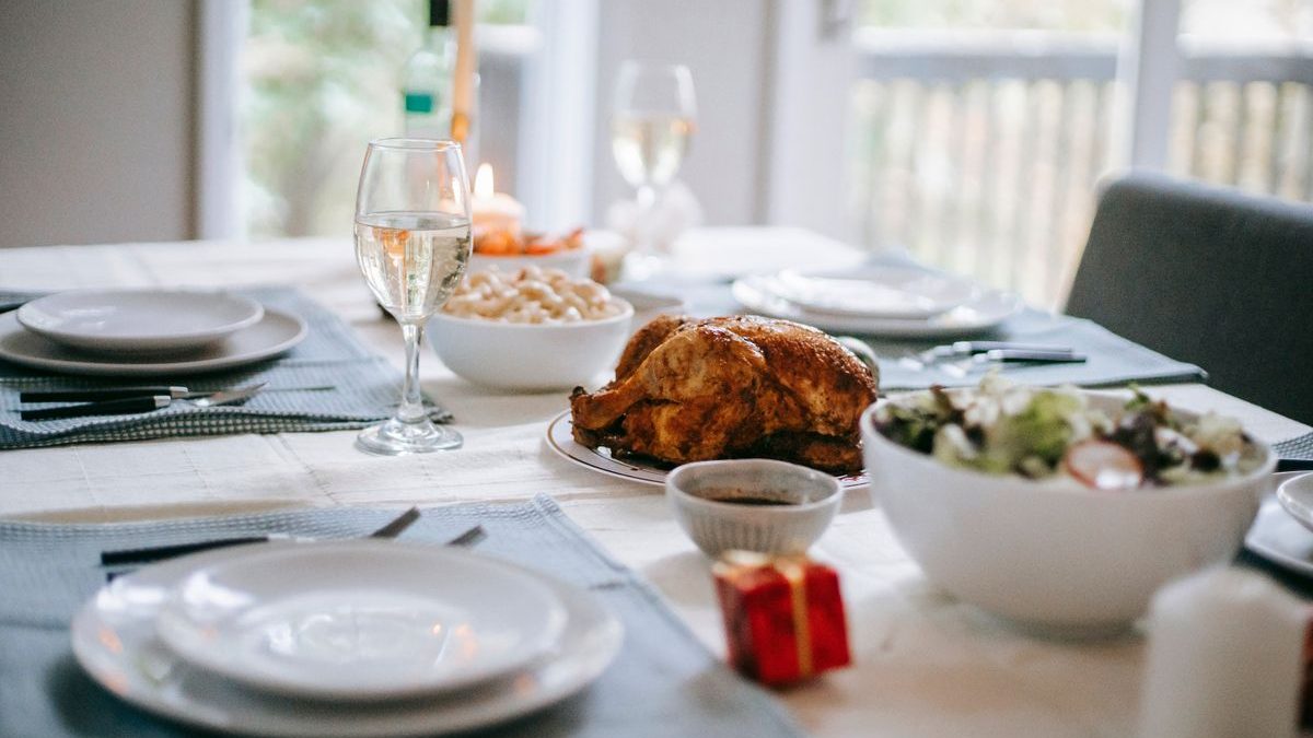 Mesa de Navidad con un pollo asado, ensalada y copas de vino blanco
